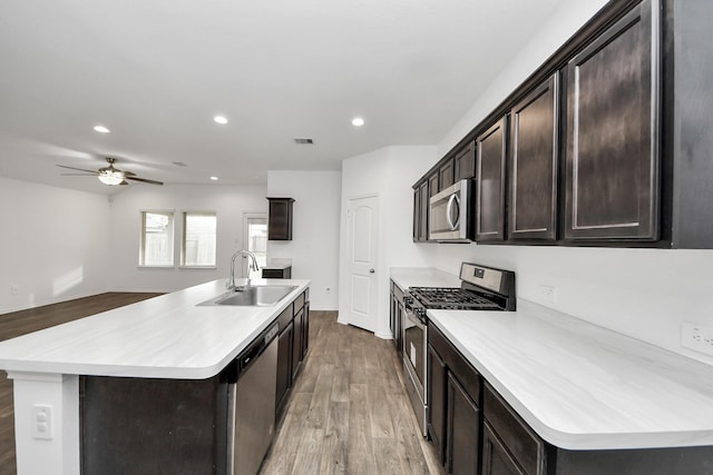 kitchen featuring sink, wood-type flooring, stainless steel appliances, and a center island with sink