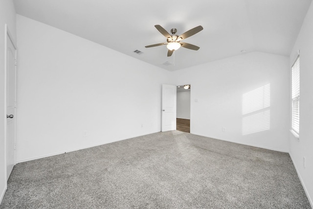 spare room with lofted ceiling, dark carpet, and ceiling fan