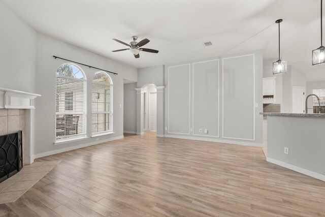 unfurnished living room featuring ceiling fan, a fireplace, light hardwood / wood-style floors, and sink