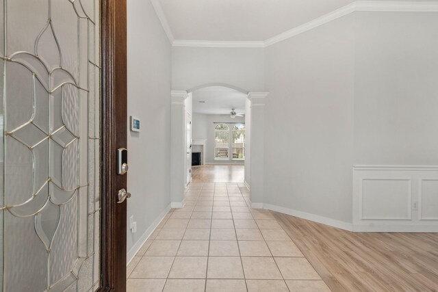 tiled entrance foyer featuring decorative columns, crown molding, and ceiling fan