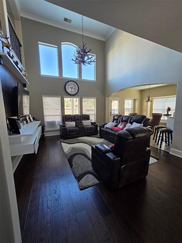 living room featuring dark hardwood / wood-style floors, plenty of natural light, ornamental molding, and an inviting chandelier