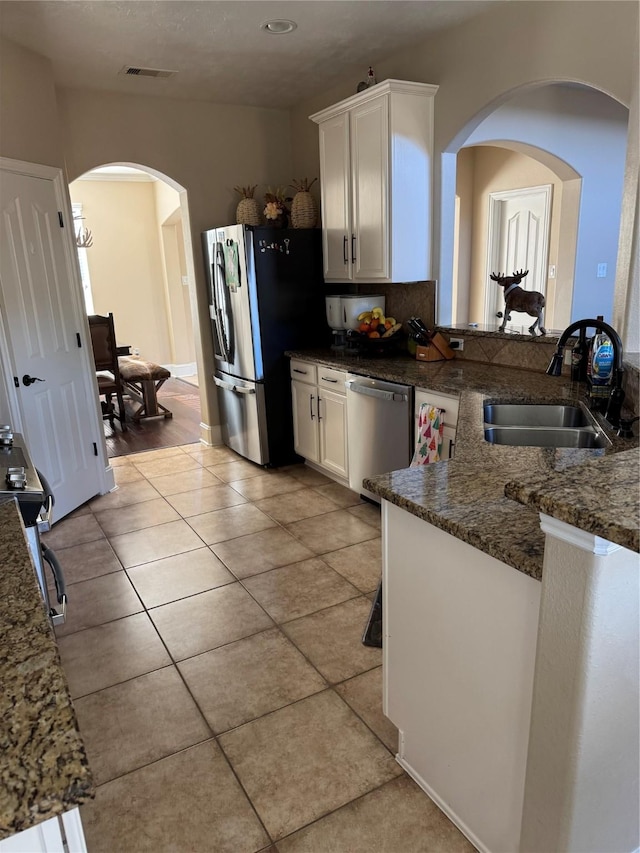 kitchen featuring light tile patterned flooring, appliances with stainless steel finishes, white cabinetry, and sink