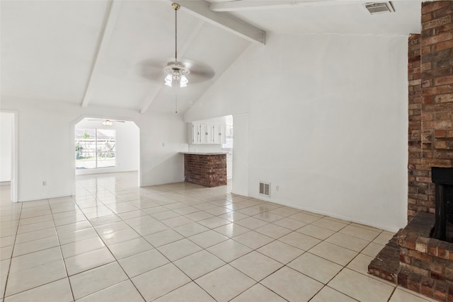 unfurnished living room with a brick fireplace, ceiling fan, light tile patterned floors, beam ceiling, and high vaulted ceiling