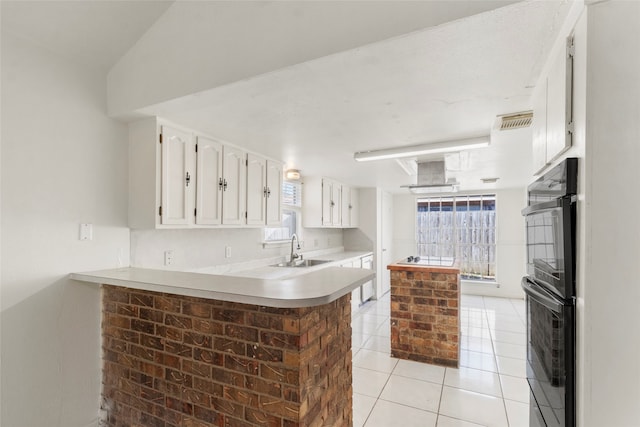 kitchen featuring sink, light tile patterned floors, kitchen peninsula, black double oven, and white cabinets