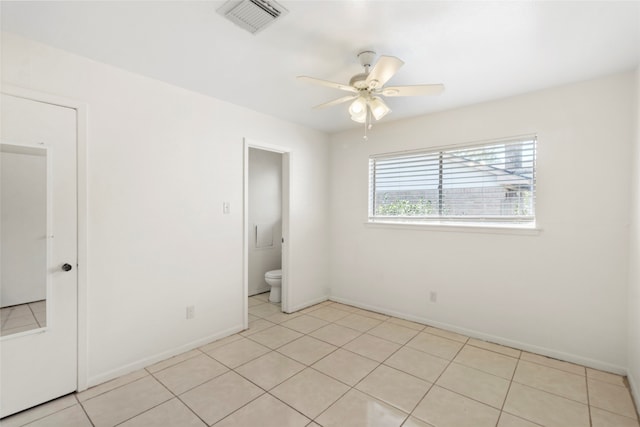 unfurnished bedroom with ceiling fan, light tile patterned flooring, and ensuite bathroom