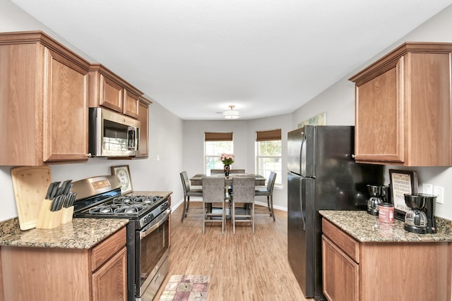 kitchen featuring appliances with stainless steel finishes, light wood-type flooring, and light stone counters