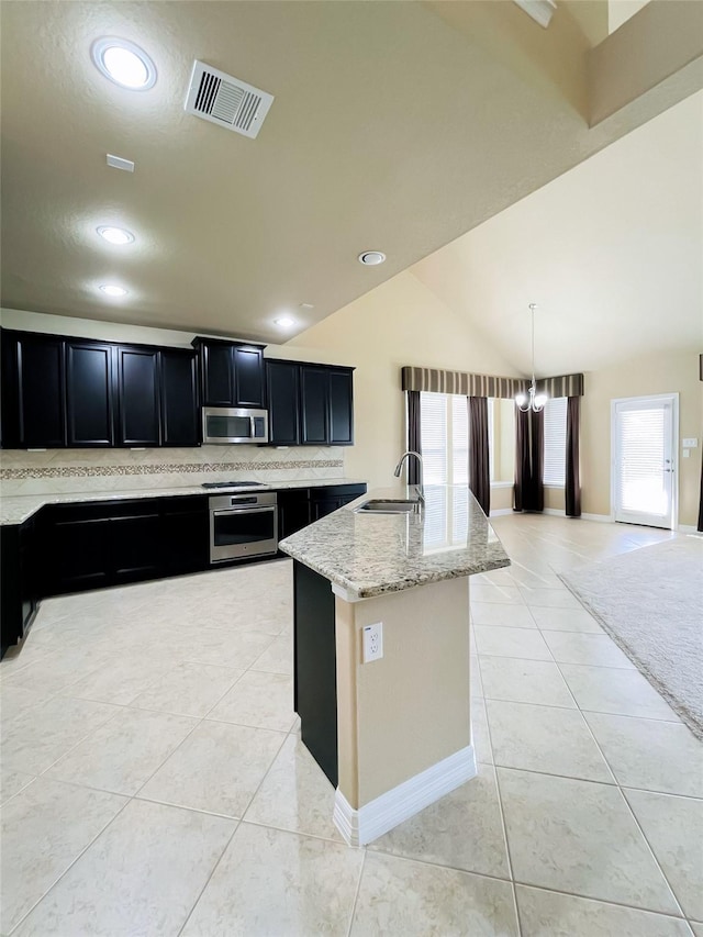 kitchen with sink, an island with sink, decorative light fixtures, light tile patterned flooring, and stainless steel appliances