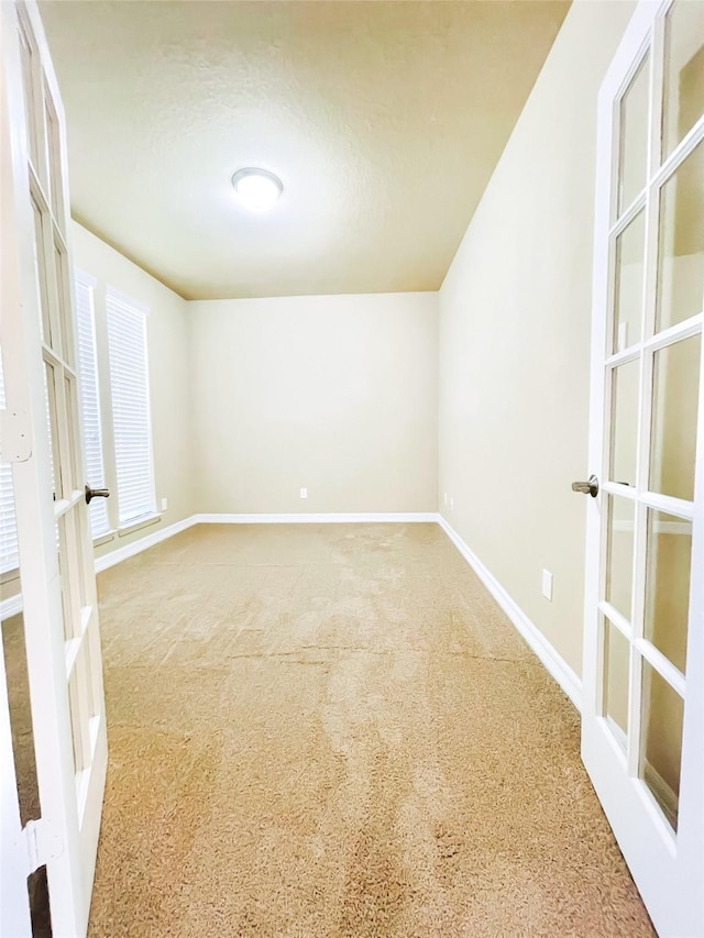 carpeted spare room featuring french doors