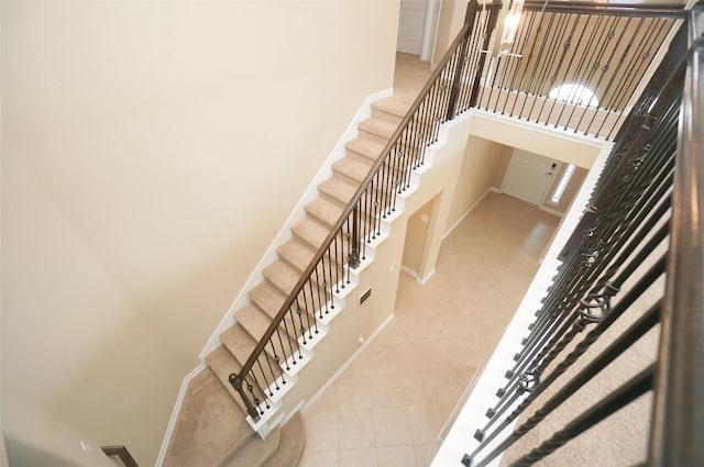 stairs with tile patterned floors, a towering ceiling, and a chandelier