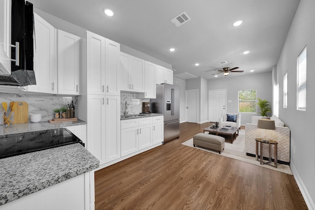 kitchen featuring high end refrigerator, white cabinetry, tasteful backsplash, and light stone countertops