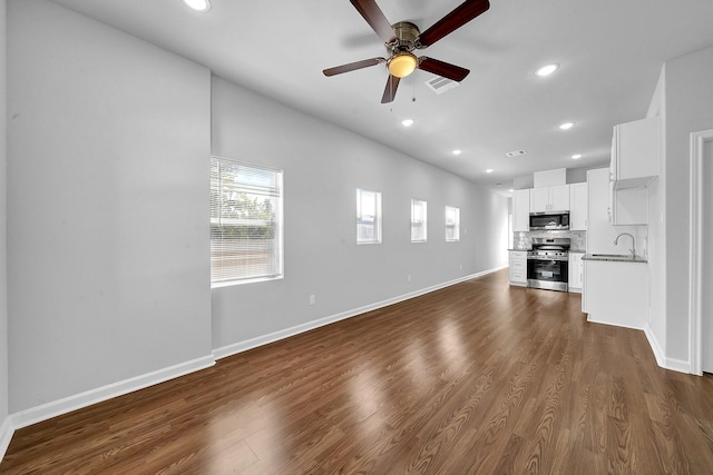 unfurnished living room featuring ceiling fan, dark hardwood / wood-style flooring, and sink