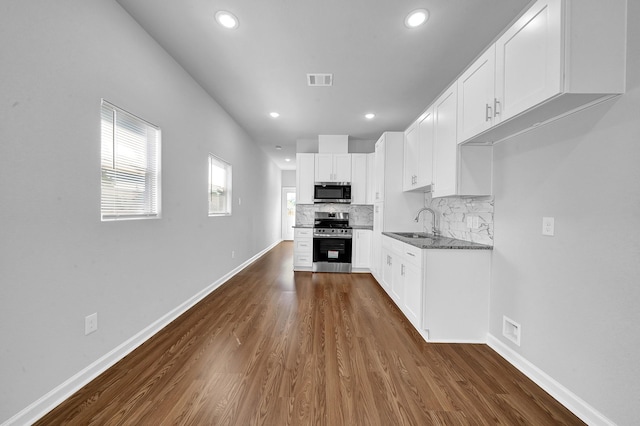 kitchen featuring sink, decorative backsplash, dark hardwood / wood-style floors, appliances with stainless steel finishes, and white cabinetry