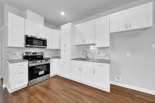 kitchen with light stone countertops, white cabinetry, sink, and stainless steel appliances