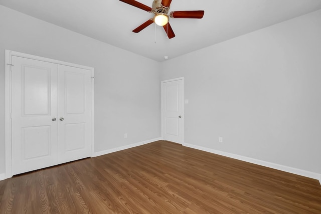 unfurnished bedroom with ceiling fan, dark wood-type flooring, and a closet