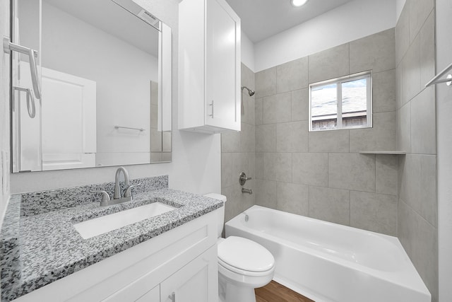 full bathroom featuring vanity, tiled shower / bath combo, and toilet