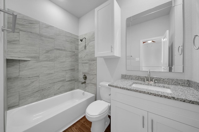 full bathroom with ceiling fan, tiled shower / bath combo, wood-type flooring, toilet, and vanity