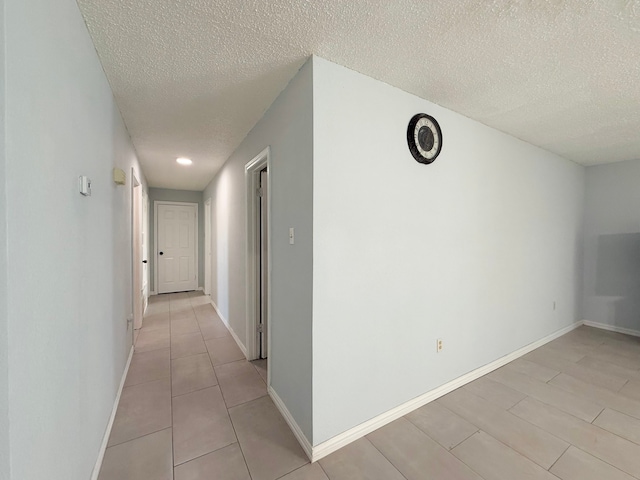 hall with light tile patterned floors and a textured ceiling