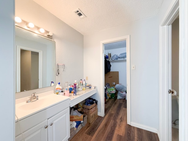 bathroom with hardwood / wood-style floors, vanity, and a textured ceiling