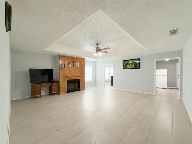 unfurnished living room featuring ceiling fan, a raised ceiling, and light tile patterned floors