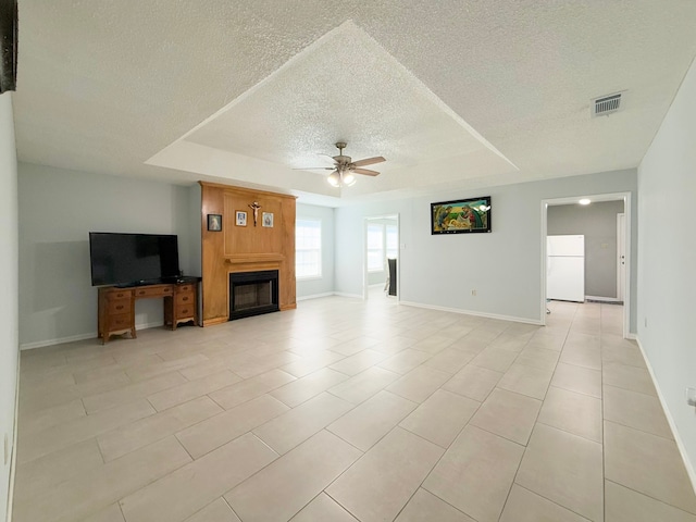 unfurnished living room with a textured ceiling, a tray ceiling, ceiling fan, and light tile patterned flooring