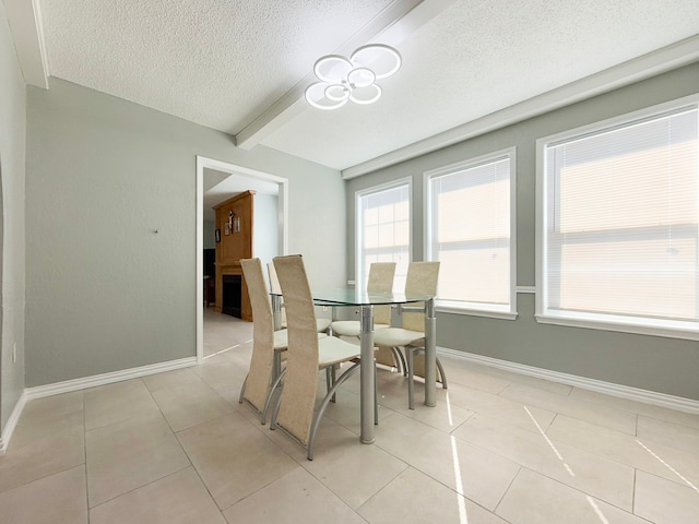 tiled dining room with beamed ceiling and a textured ceiling