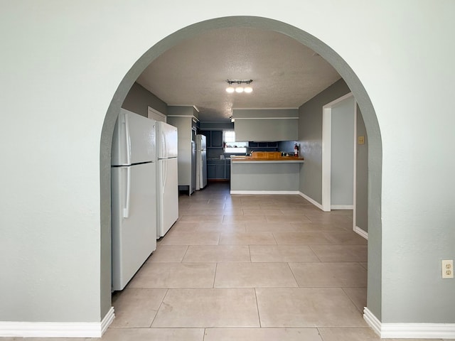 kitchen featuring wood counters, light tile patterned flooring, a textured ceiling, and white refrigerator