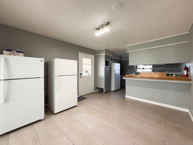 kitchen with butcher block counters, a textured ceiling, and white refrigerator