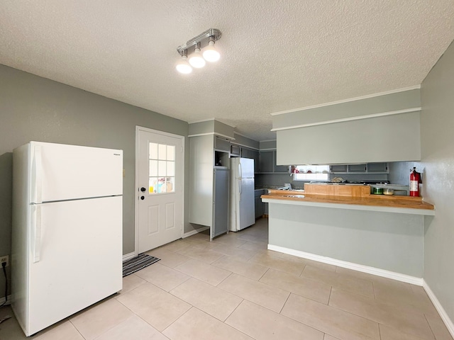 kitchen with wood counters, white fridge, kitchen peninsula, and a textured ceiling