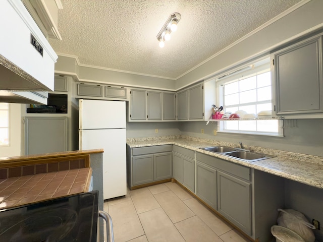 kitchen featuring gray cabinets, sink, white fridge, and light tile patterned flooring