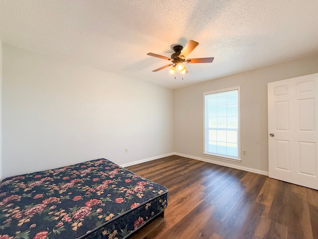 bedroom with a textured ceiling, dark hardwood / wood-style flooring, and ceiling fan