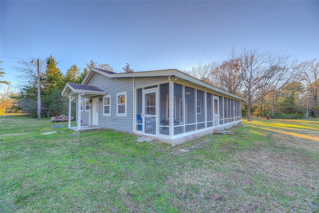 view of property exterior with a lawn and a sunroom