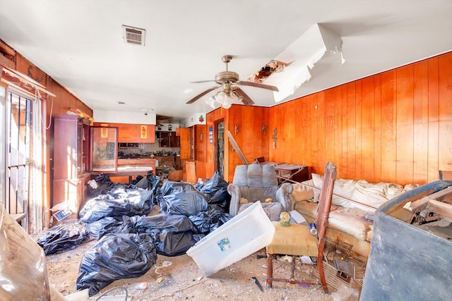 misc room featuring ceiling fan and wooden walls