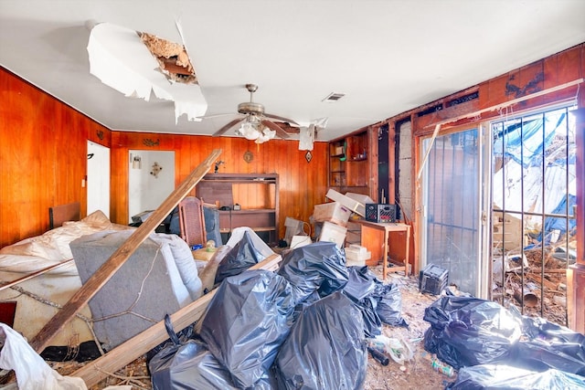 misc room featuring ceiling fan and wood walls