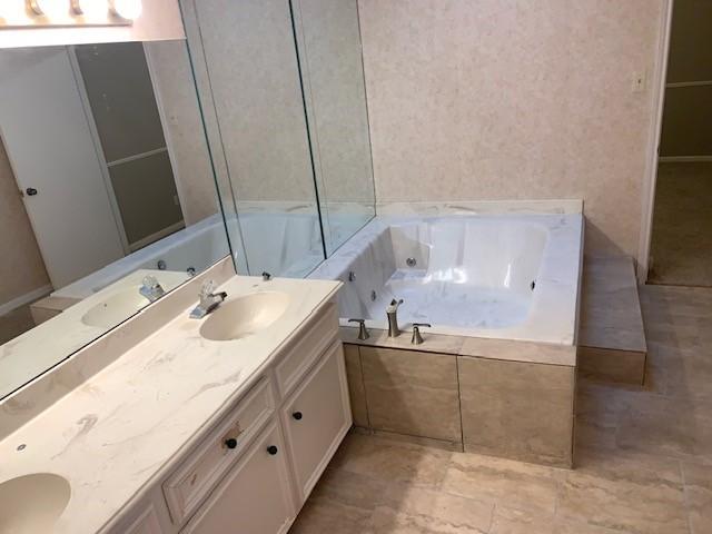 bathroom featuring vanity and a relaxing tiled tub