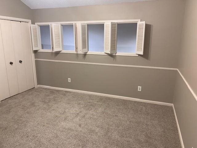 unfurnished bedroom featuring light colored carpet, a closet, and lofted ceiling