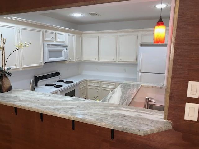 kitchen featuring white cabinets, pendant lighting, white appliances, and sink