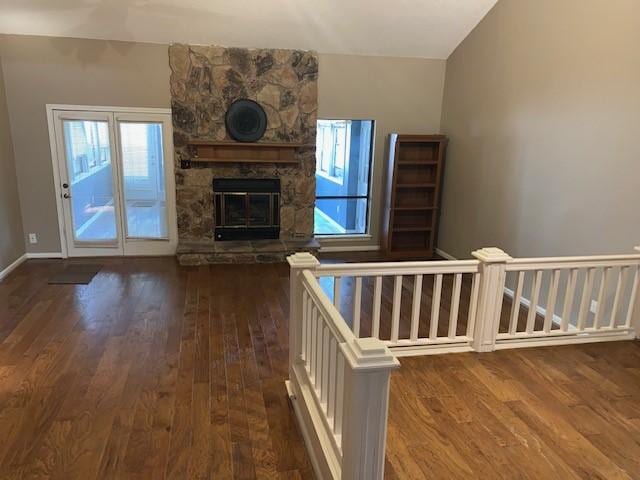 unfurnished living room featuring a stone fireplace and dark hardwood / wood-style floors