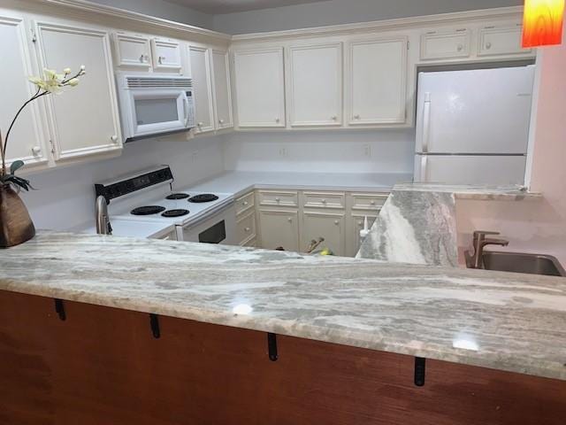 kitchen featuring light stone counters, sink, white cabinets, and white appliances