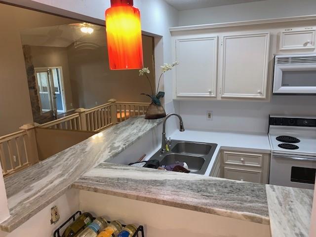 kitchen featuring white appliances, white cabinetry, and sink