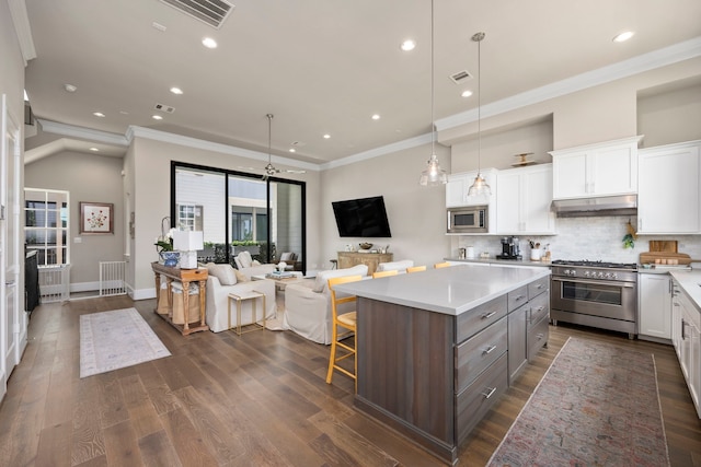 kitchen with tasteful backsplash, stainless steel appliances, white cabinets, a kitchen island, and hanging light fixtures