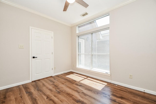 empty room with plenty of natural light, dark hardwood / wood-style floors, and ornamental molding