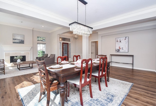 dining room with a tile fireplace, crown molding, a chandelier, and dark hardwood / wood-style floors