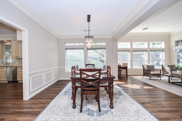 dining space with dark wood-type flooring, an inviting chandelier, crown molding, and sink