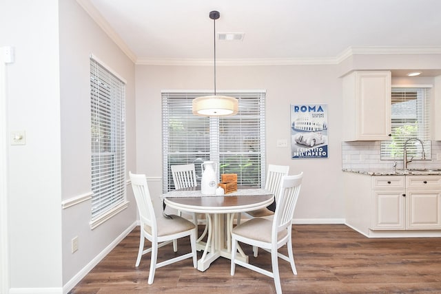 dining space with dark hardwood / wood-style floors, ornamental molding, and sink