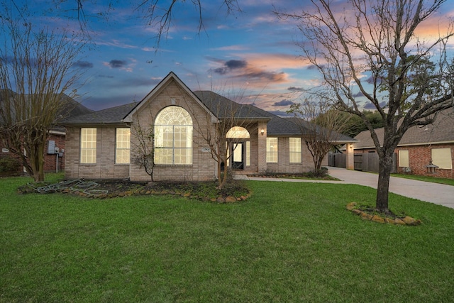 view of front of property with a yard, driveway, and brick siding