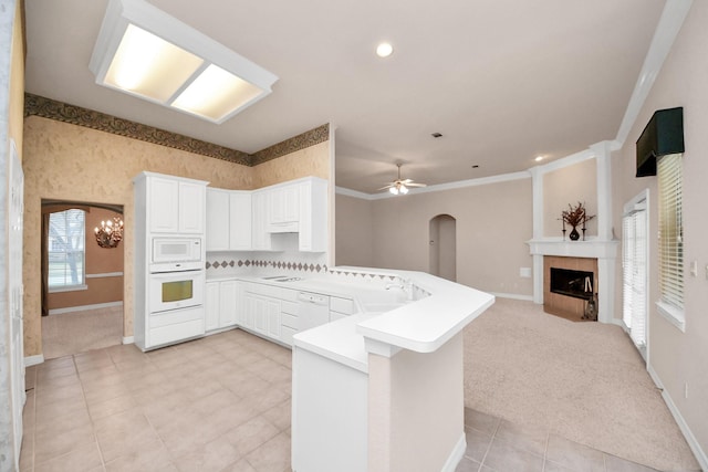 kitchen with light carpet, a fireplace, white appliances, and kitchen peninsula