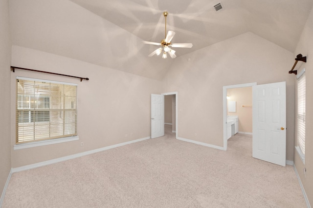 unfurnished bedroom featuring multiple windows, connected bathroom, and light colored carpet