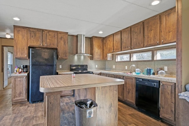 kitchen with dark hardwood / wood-style flooring, a wealth of natural light, wall chimney range hood, black appliances, and a kitchen island