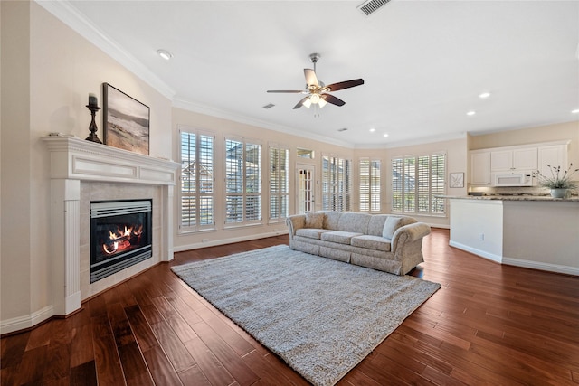 living room with ceiling fan, a fireplace, dark hardwood / wood-style flooring, and crown molding