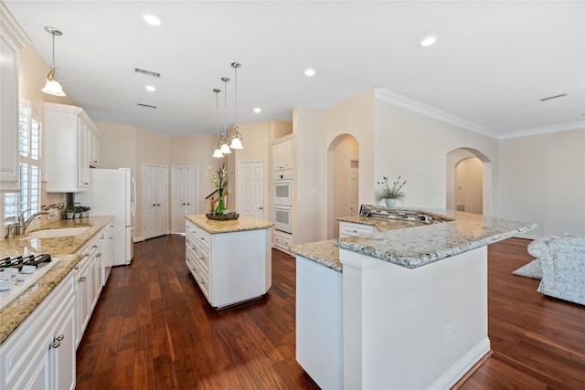 kitchen with hanging light fixtures, sink, white cabinetry, and a kitchen island